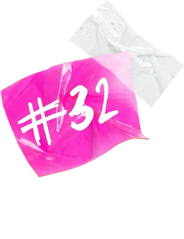 Nahaufnahme einer gefalteten, leuchtend pinkfarbenen Plastikfolie mit der weißen Aufschrift '#32', darunter ein weißer gepunkteter Pfeil, der zu weißen Herzen führt.